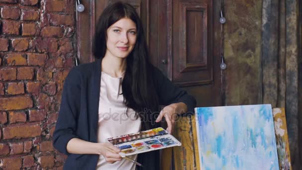 Ritratto al rallentatore di giovane artista donna in piedi vicino immagine finita e sorriso in macchina fotografica — Video Stock