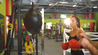 Genç kadın boksör kum torbası öncesi maç ısınma sırasında onu antrenman ör boks kulübü ile vurmak