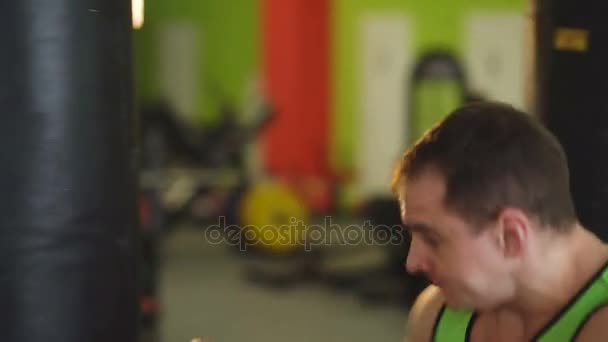 Joven boxeador practicando en un saco de boxeo con ayuda de una mujer — Vídeos de Stock