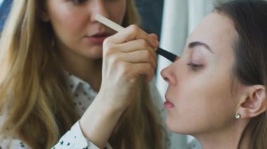 Genç makyöz, ağır çekim yapan bir kız güzel makyaj closeup önce önemli bir olay