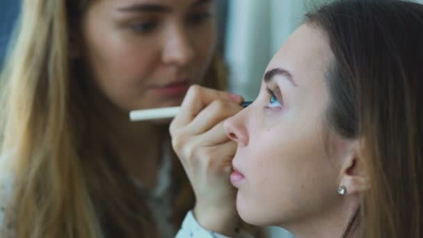 Jovem maquilhadora faz uma menina bela maquiagem para olhos close-up antes de um evento importante — Vídeo de Stock