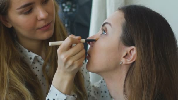 Slow motion of young make-up artist makes a girl beautiful makeup closeup before an important event — Stock Video