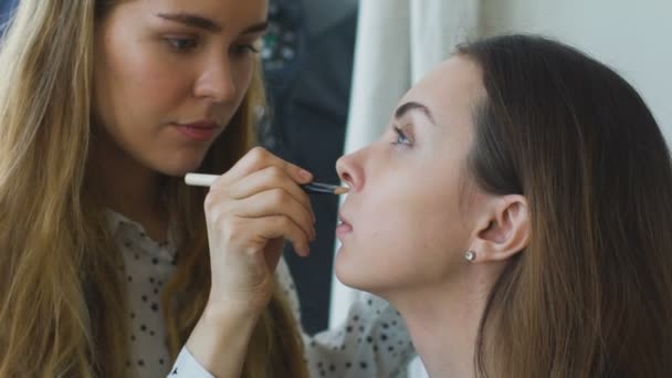 Rallentare il movimento di giovane make-up artist rende una ragazza bella trucco primo piano prima di un evento importante — Video Stock