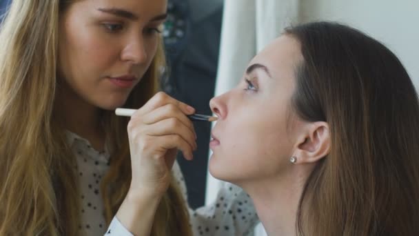 Slow motion van jonge Visagist maakt een meisje mooie make-up close-up vóór een belangrijke gebeurtenis — Stockvideo