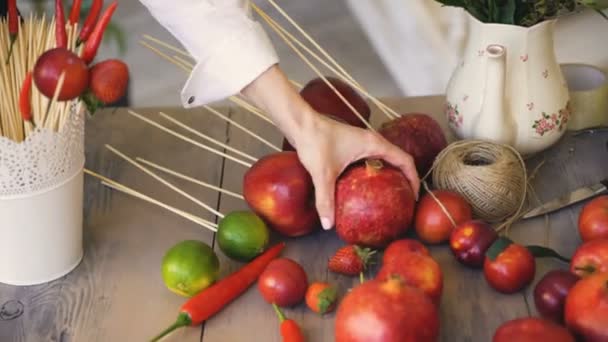 Žena kuchař bere granátové jablko z dřevěného stolu s ovocem a zeleninou, příprava před vařením