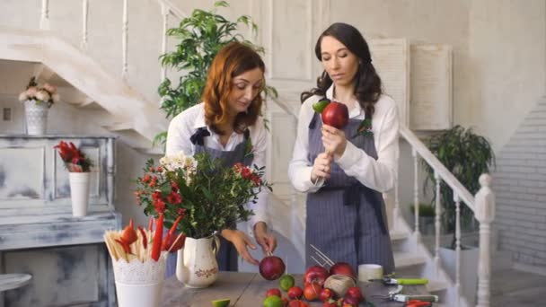 Dois floristas de chef bonito jovem trabalham na loja de frutas de flores fazendo buquê de frutas e vegetais — Vídeo de Stock