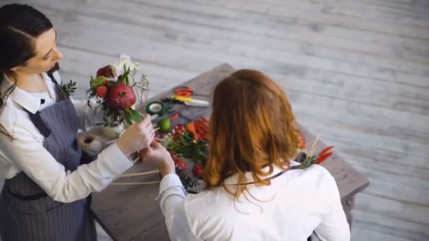 Dois floristas de chef bonito jovem trabalham na loja de frutas de flores fazendo buquê de frutas e vegetais — Vídeo de Stock