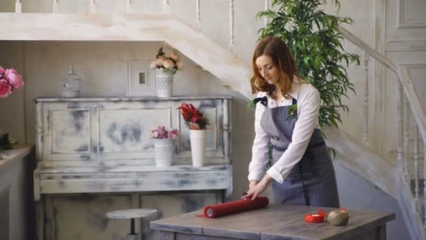 Jeune fleuriste beau papier artisanal coupé pour bouquet packink en studio — Video