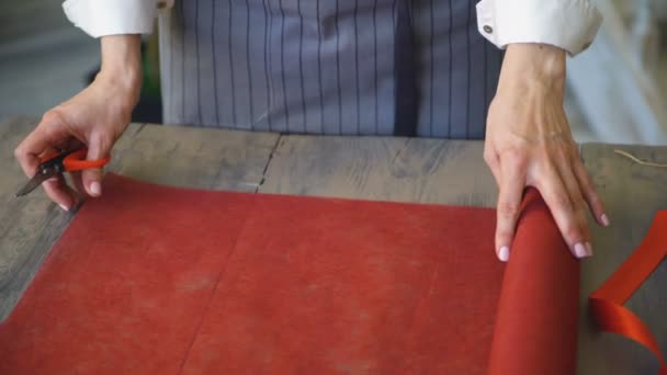 Joven florista guapo corte de papel artesanal para ramo de packink en primer plano estudio — Vídeo de stock