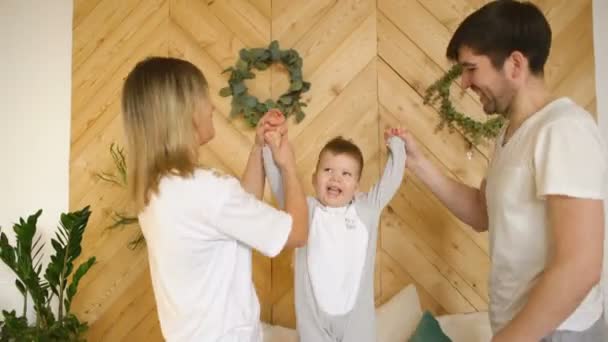 Küçük oğlu ile genç bir aile yatak yatak odasında oynamak — Stok video