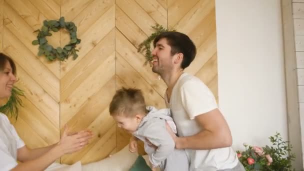 Una familia joven con un hijo pequeño jugar en la cama en el dormitorio — Vídeo de stock