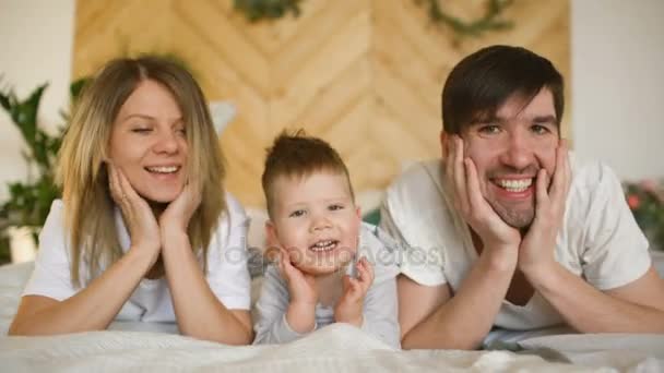 在卧室里一个可爱的家庭在床上摆出一副笑脸的画像 — 图库视频影像