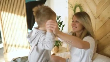Genç anne ile 3 yaşındaki küçük oğlu pijama giymiş yıllarını yatakta oynuyor