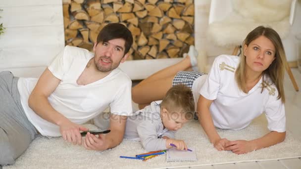 Père homme mère regarder la télévision tandis que leur fils dessiner dans leur salon — Video