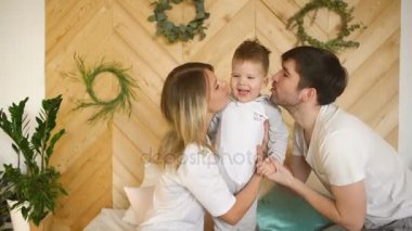 Küçük oğlu ile genç bir aile yatakta oynamak ve öp onu yatak odasında gülümseyen