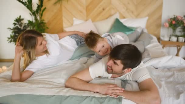 A young family with little son play on bed in the bedroom — Stock Video