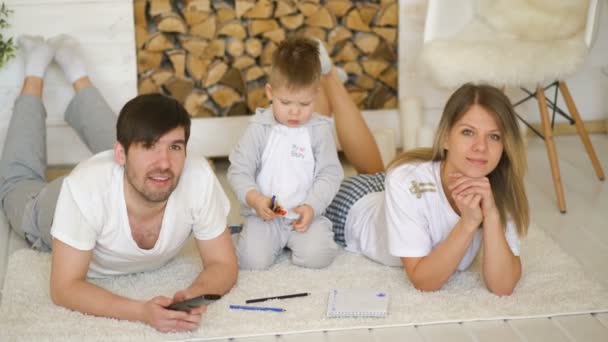 Pai homem mãe assistir TV enquanto seu filho desenhar quadro em sua sala de estar — Vídeo de Stock
