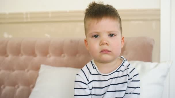 Smutný kluk sedí na gauči vypadá ve fotoaparátu pak úsměv v obývacím pokoji — Stock video