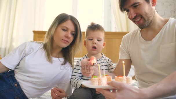 Mosolyogva család ünnepli a fiam születésnapja együtt, mielőtt fúj gyertyák, a torta — Stock videók