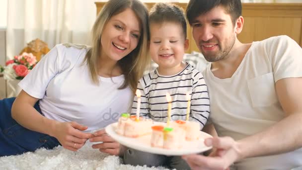 Mosolyogva család ünnepli a fiam születésnapja együtt, mielőtt fúj gyertyák, a torta — Stock videók