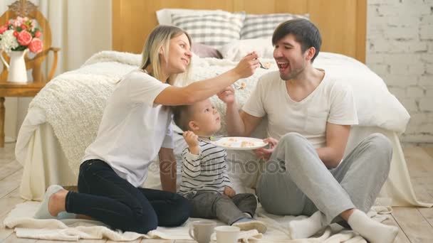 Baba ve anne ile onun doğum günü kutluyor küçük sevimli çocuk yemek pasta yatak odasında — Stok video