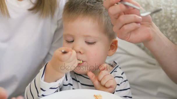 Pequeño niño adorable celebrando su cumpleaños con padre y madre comer pastel y beber té — Vídeo de stock