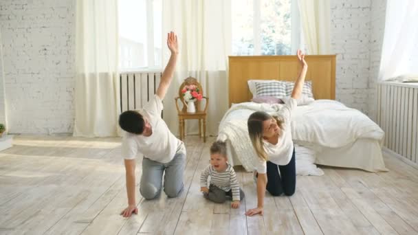 Famiglia che fa esercizi ginnici in camera da letto a casa - educazione alla vita sana — Video Stock