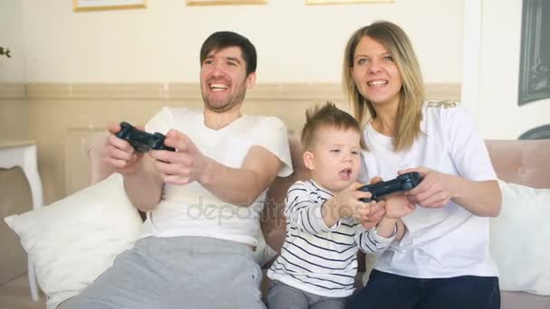Padre y madre de familia feliz jugar videojuego con su hijo tomando gamepad en casa — Vídeo de stock