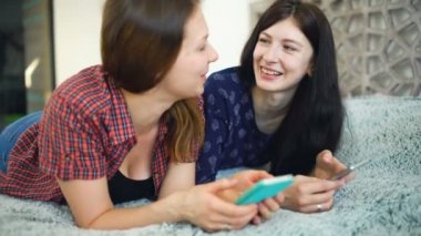 Bir akıllı telefon olarak sosyal medya paylaşımı ve konuşurken iki mutlu kadın arkadaş
