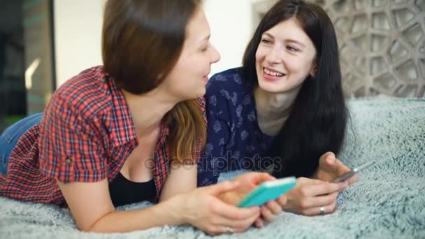 Дві щасливі жінки друзі діляться соціальними мережами в смартфоні і розмовляють — стокове відео
