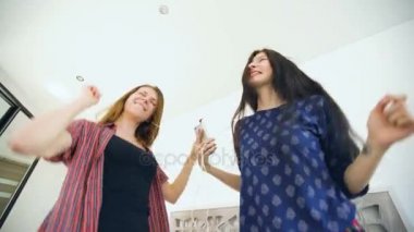 Genç kadın kulaklık ile bir yatak üzerinde dans çift ve evde yatak odasında eğlenin mutlu