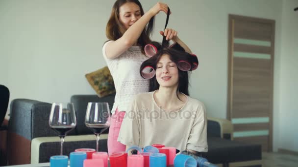 Duas mulheres felizes amigos fazer divertido curler penteado uns aos outros e se divertir em casa — Vídeo de Stock