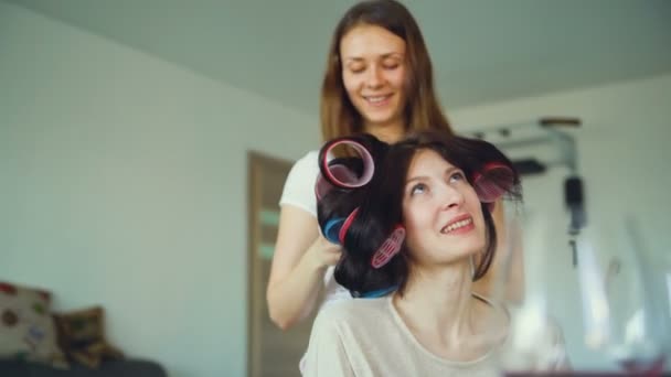 Dwie kobiety szczęśliwy, przyjaciele zrobić zabawy curler fryzurę, siebie i zabawy w domu — Wideo stockowe