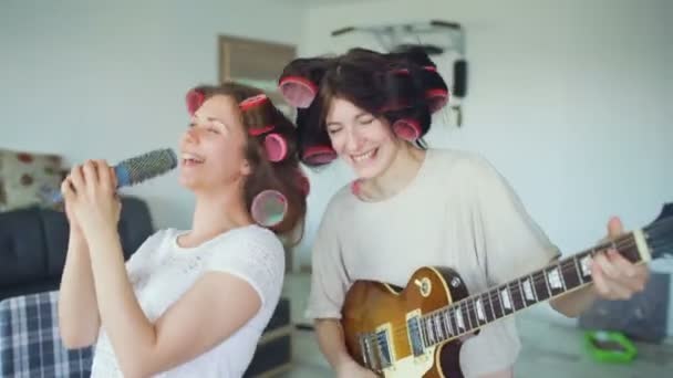 Duas meninas engraçadas cantando com pente e tocando guitarra elétrica dança, cantar e ter alegria em casa — Vídeo de Stock