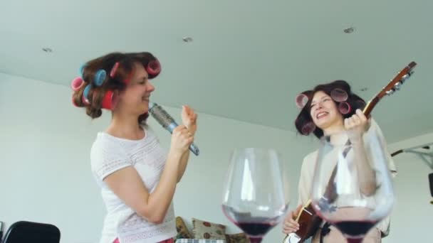 Slow motion van twee grappige meisjes zingen met kam en elektrische gitaar spelen dansen en zingen — Stockvideo