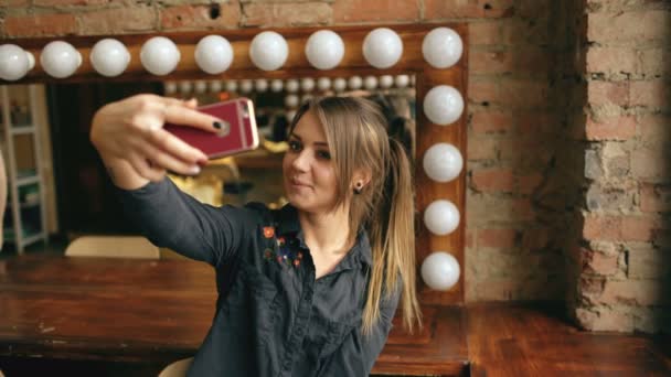 Mulher bonita fazendo retrato selfie em um smartphone em camarim dentro de casa — Vídeo de Stock