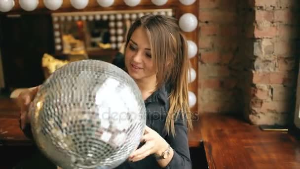 Gyönyörű fiatal nő, disco labdát jelentő és mosolyogva bent a stúdióban — Stock videók