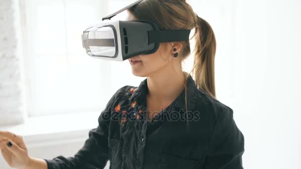 Vrouw in Vr headset opzoeken en proberen te raken van objecten in virtuele werkelijkheid in witte kamer binnenshuis — Stockvideo