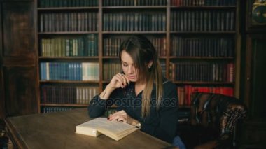 Genç ciddi kadın kapalı Üniversitesi kitaplığındaki kitap okumak