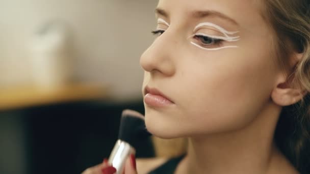 Maquillaje artista hace joven actriz chica hermoso maquillaje para la cara antes de bailar perfomance en interiores — Vídeos de Stock