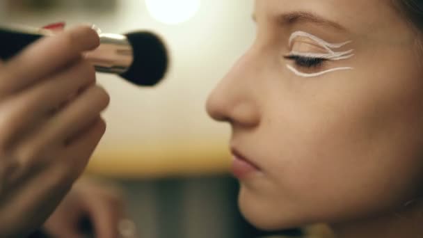 Maquillaje artista hace joven actriz chica hermoso maquillaje para la cara antes de bailar perfomance en interiores — Vídeo de stock