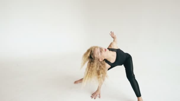 Сучасна красива дівчина-підліток танцює сучасний на білому тлі в приміщенні — стокове відео