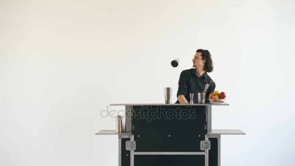 Professinal bartender man juggling bottles and shaking cocktail at mobile bar table on white background studio indoors — Stock Video