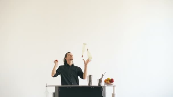 Camarero profesional haciendo malabarismos con botellas y batiendo cócteles en la mesa del bar móvil sobre fondo blanco — Vídeo de stock