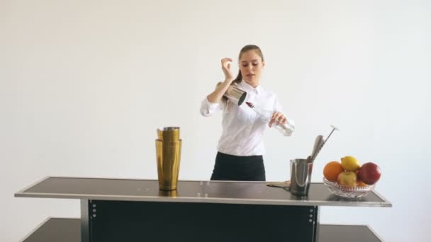 Professinal bartender girl jonglering flaskor och skakar cocktail på mobila barbord på vit bakgrund studio inomhus — Stockvideo