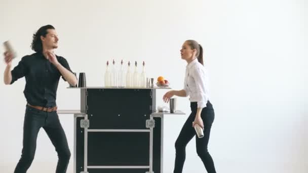 Професійний бармен чоловік і жінка жонглюють пляшки і струшують коктейль на мобільному барному столі на білому тлі — стокове відео