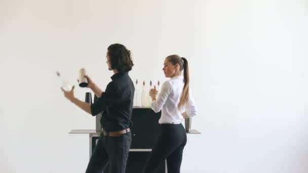 Professeur barman homme et femme jonglant bouteilles et cocktail secouant à la table de bar mobile sur fond blanc studio — Video