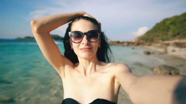 Mulher bonita tomando selfie usando telefone na praia sorrindo e gostando de viajar estilo de vida em férias — Vídeo de Stock