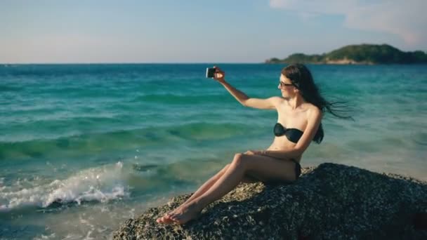 Mulher bonita tomando selfie usando telefone na praia sorrindo e gostando de viajar estilo de vida em férias — Vídeo de Stock