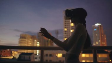 Sanal gerçeklik kulaklık kullanarak ve geceleri Vr deneyimi olan çatı katı terasında genç kadın